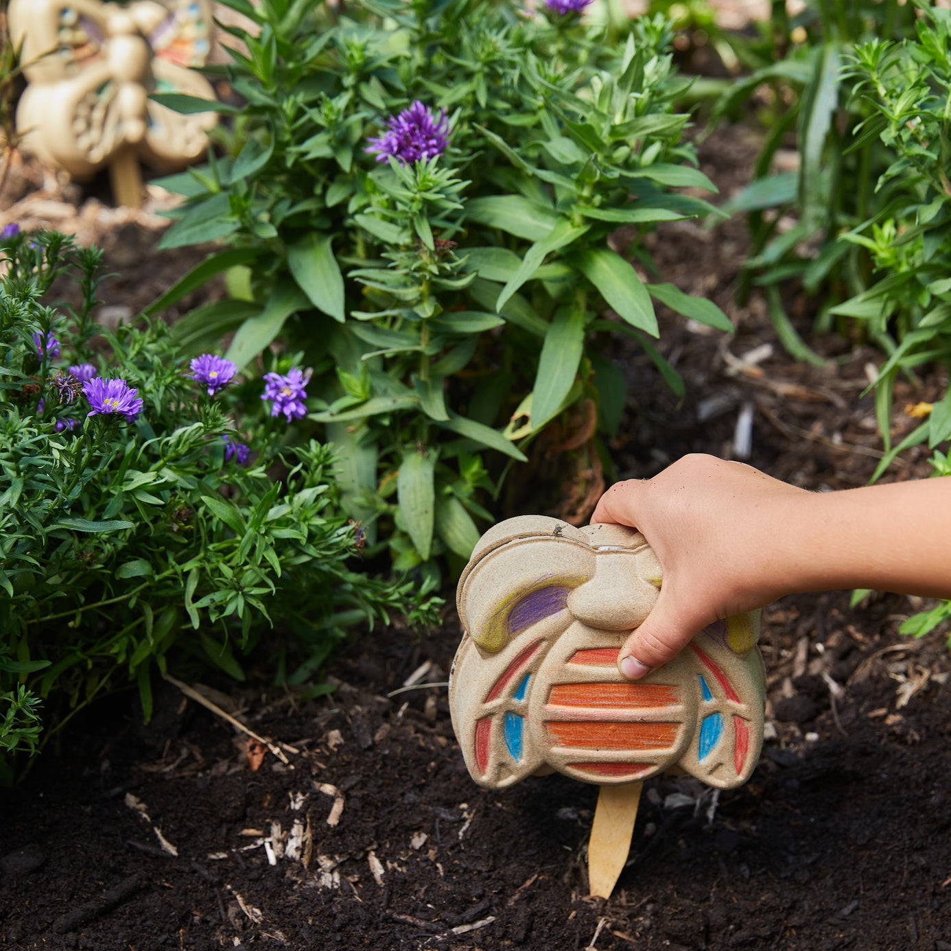 Child planting a bumble bee Curious Critters Activity Kit in a garden