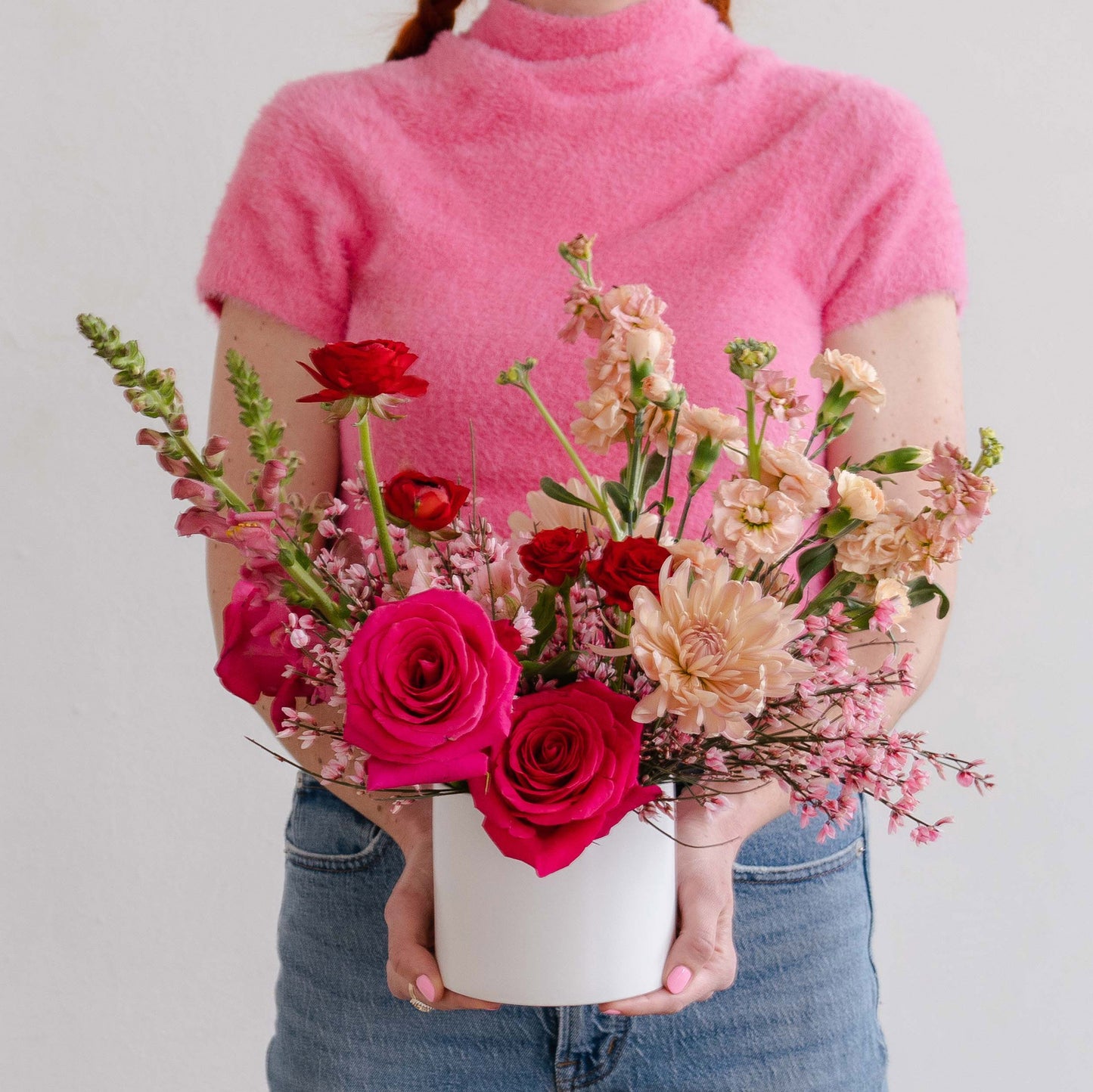 Woman holding Valentine's Day flowers in shades of pink, red, and peach