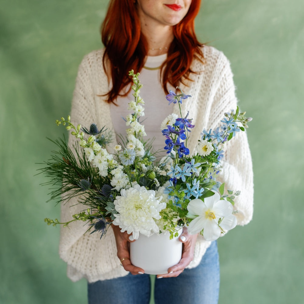 Meg Blancato holds white and blue holiday flowers from San Diego Flower Shop Native Poppy