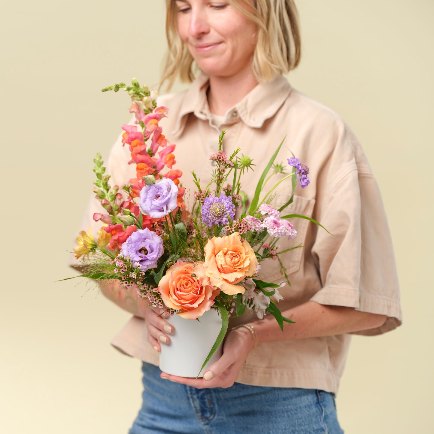 Woman holding petite seasonal flower arrangement from Native Poppy