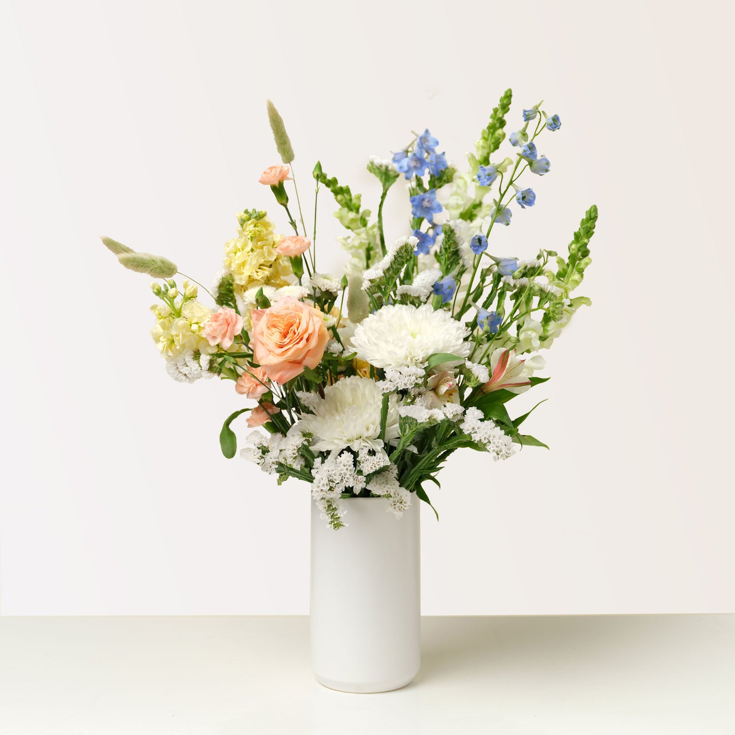 Tall white and pastel flower arrangement in white vase