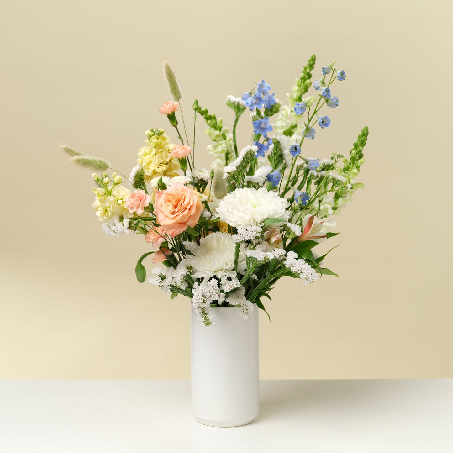 Tall white and pastel flower arrangement in white vase