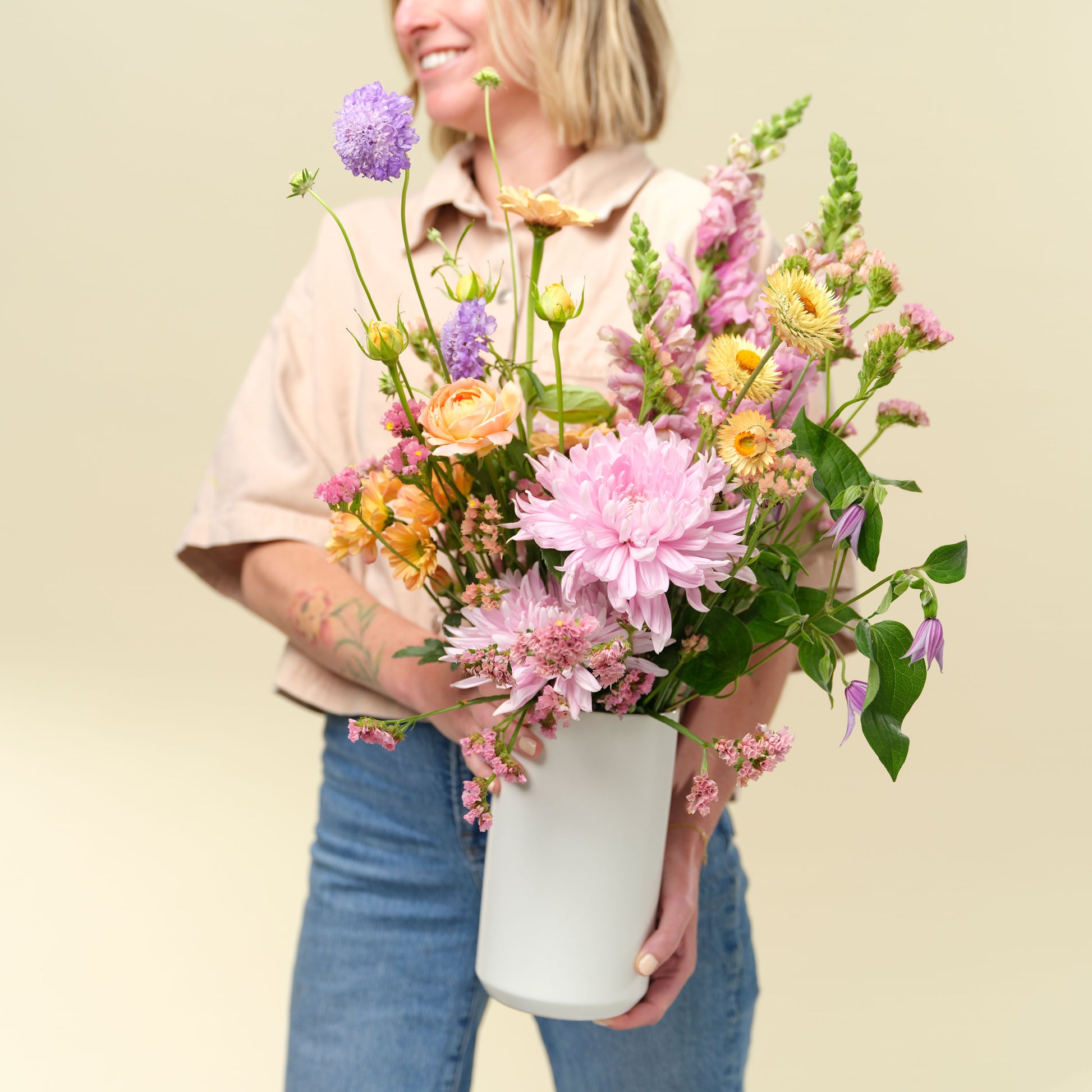 Woman holds a flower arrangement in tall vase from Native Poppy