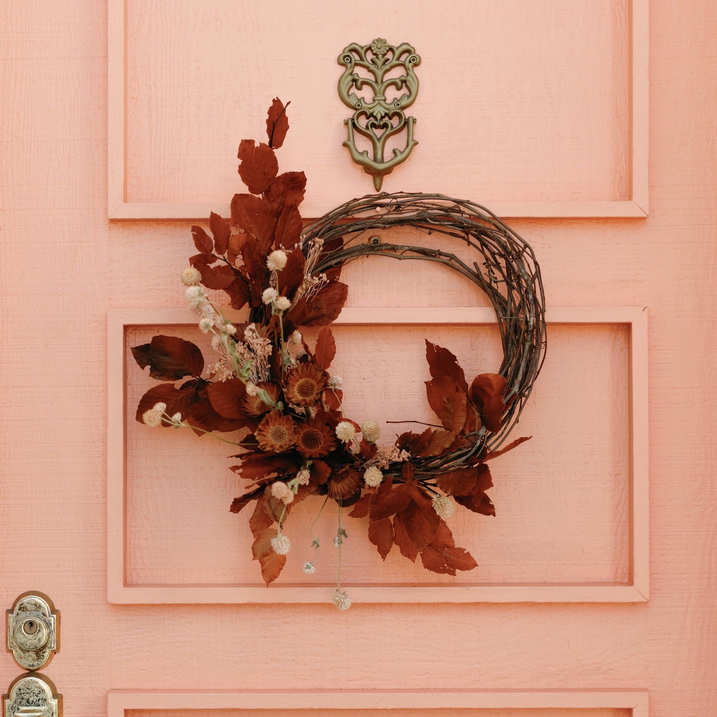 Umber and orange autumn leaves made into a wreath on grapevine frame with dried floral accents