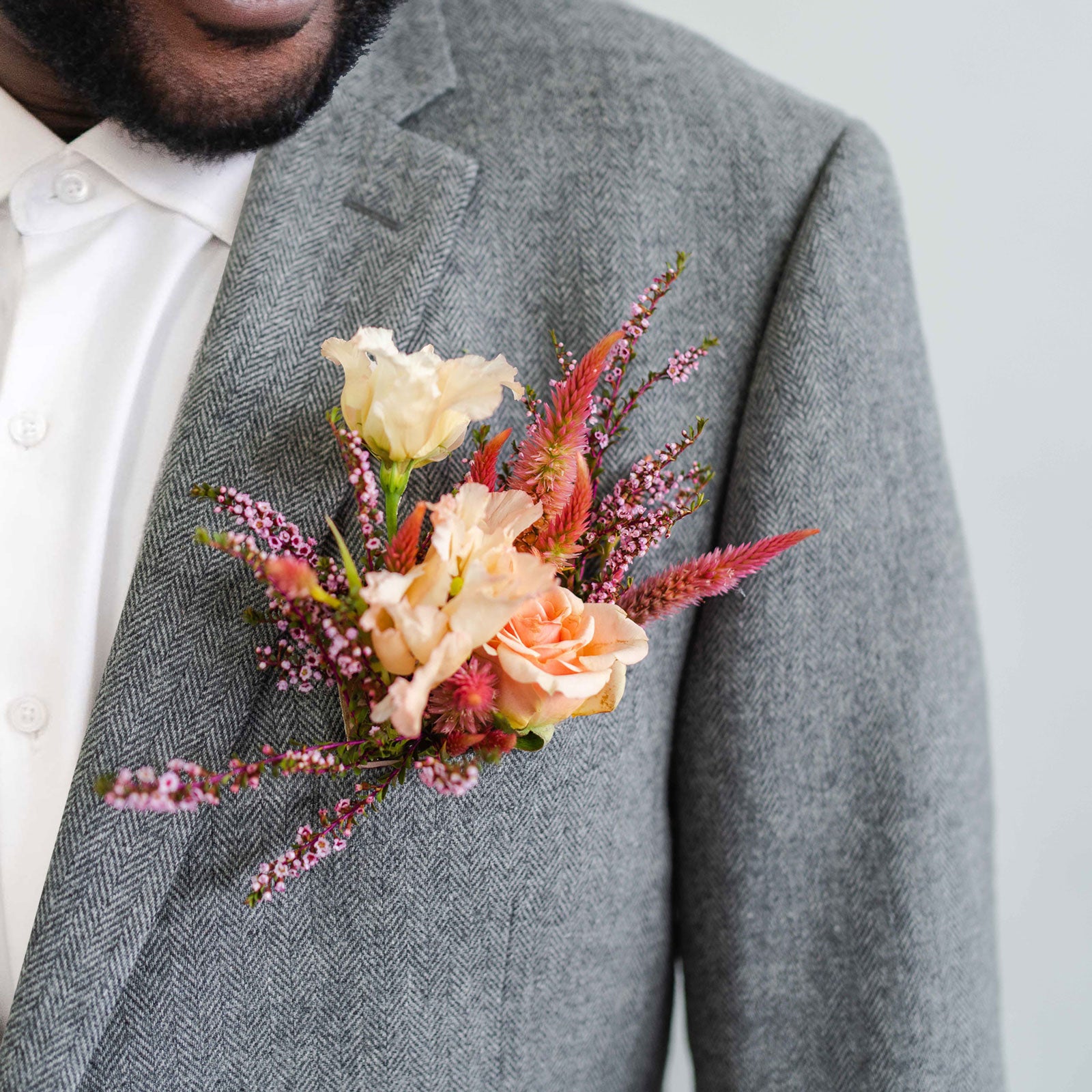 Brightly colored floral Pocket Boutonnière in a suit jacket pocket worn by a bearded man