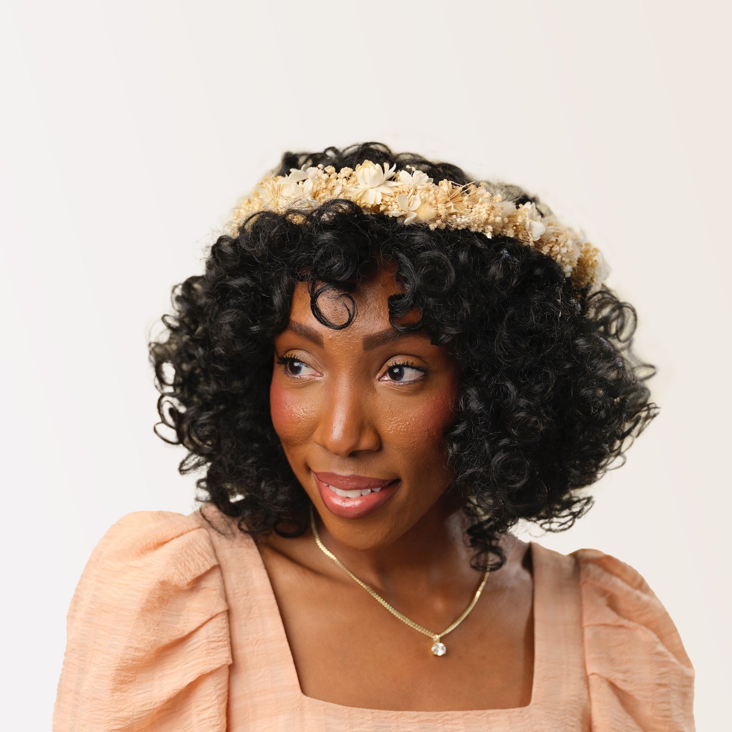 Woman with dark curly hair wearing neutral dried flower crown