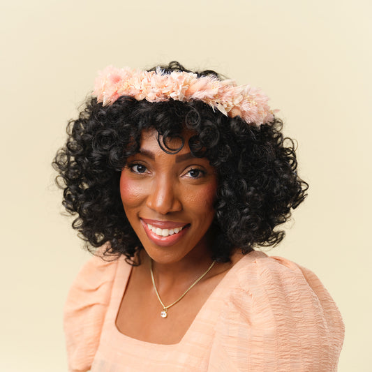 Woman with dark curly hair wearing pink dried flower crown