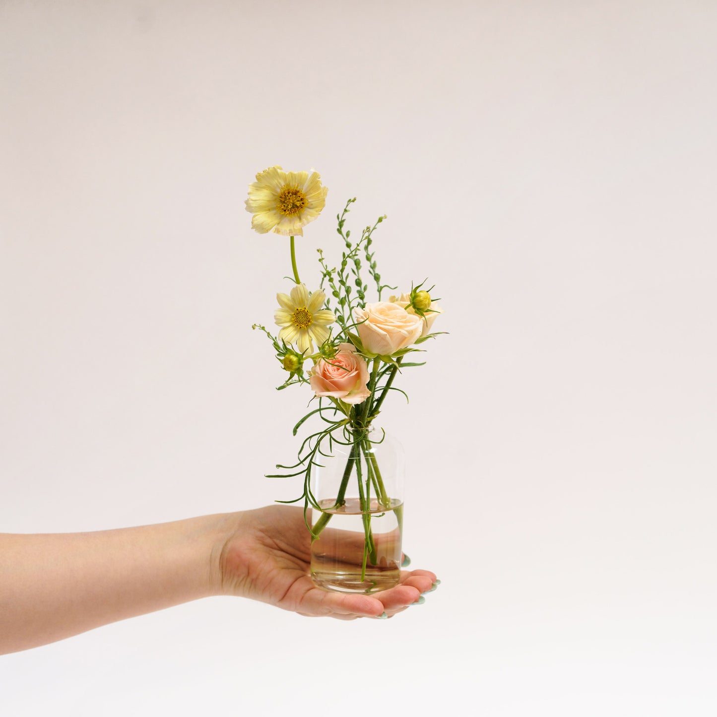 Person holding a Small glass bud vase flower arrangement