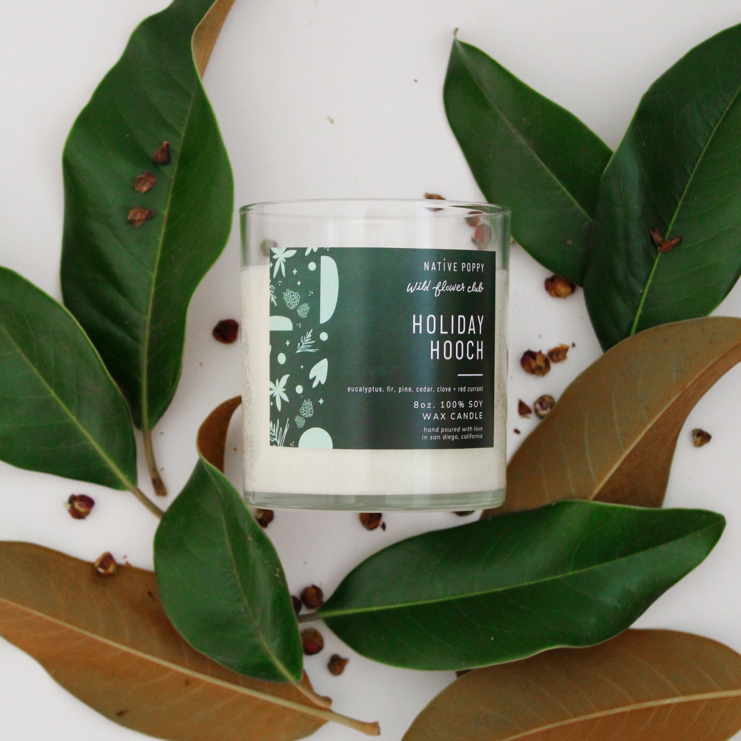 Holiday Hooch candle from Native Poppy with green fall foliage