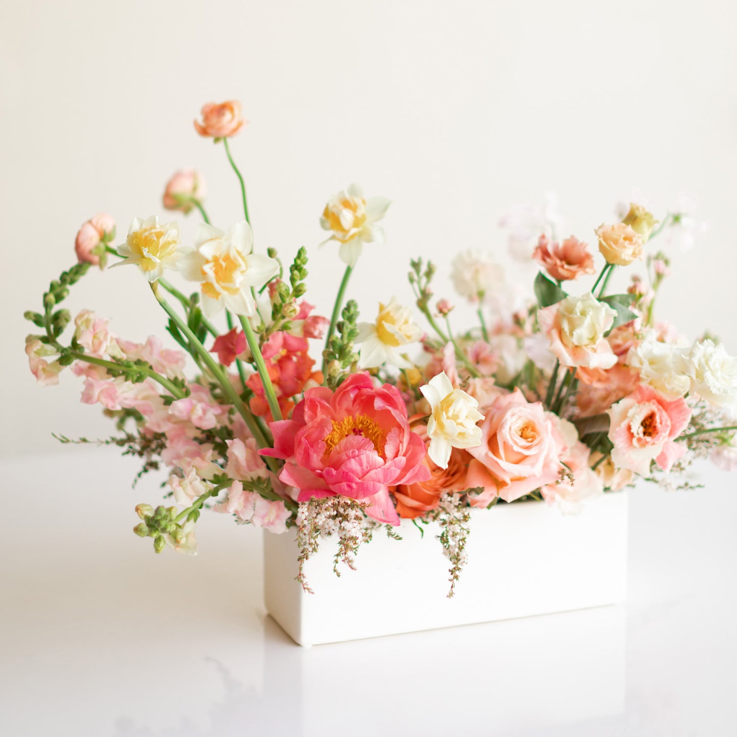 Long and Low Flower Arrangement with peonies, daffodils, roses, and other pink toned flowers